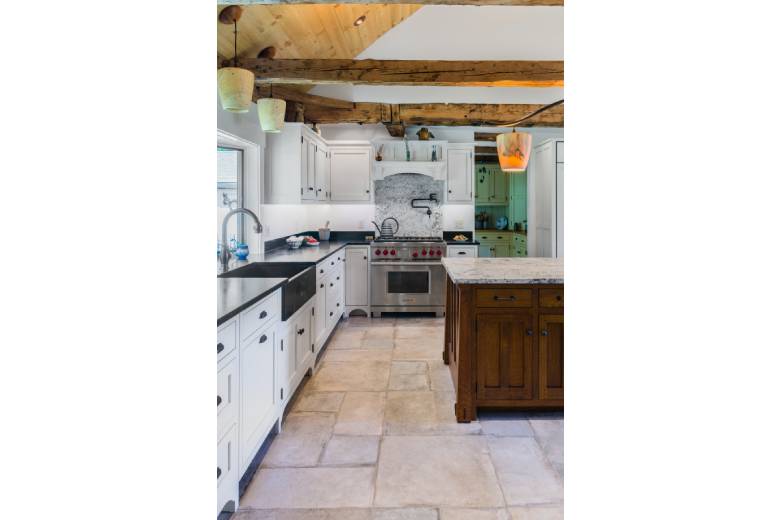 Large kitchen with natural wood beams and white cabinets