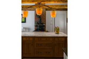 Island with a chandelier hanging from natural beams in a kitchen