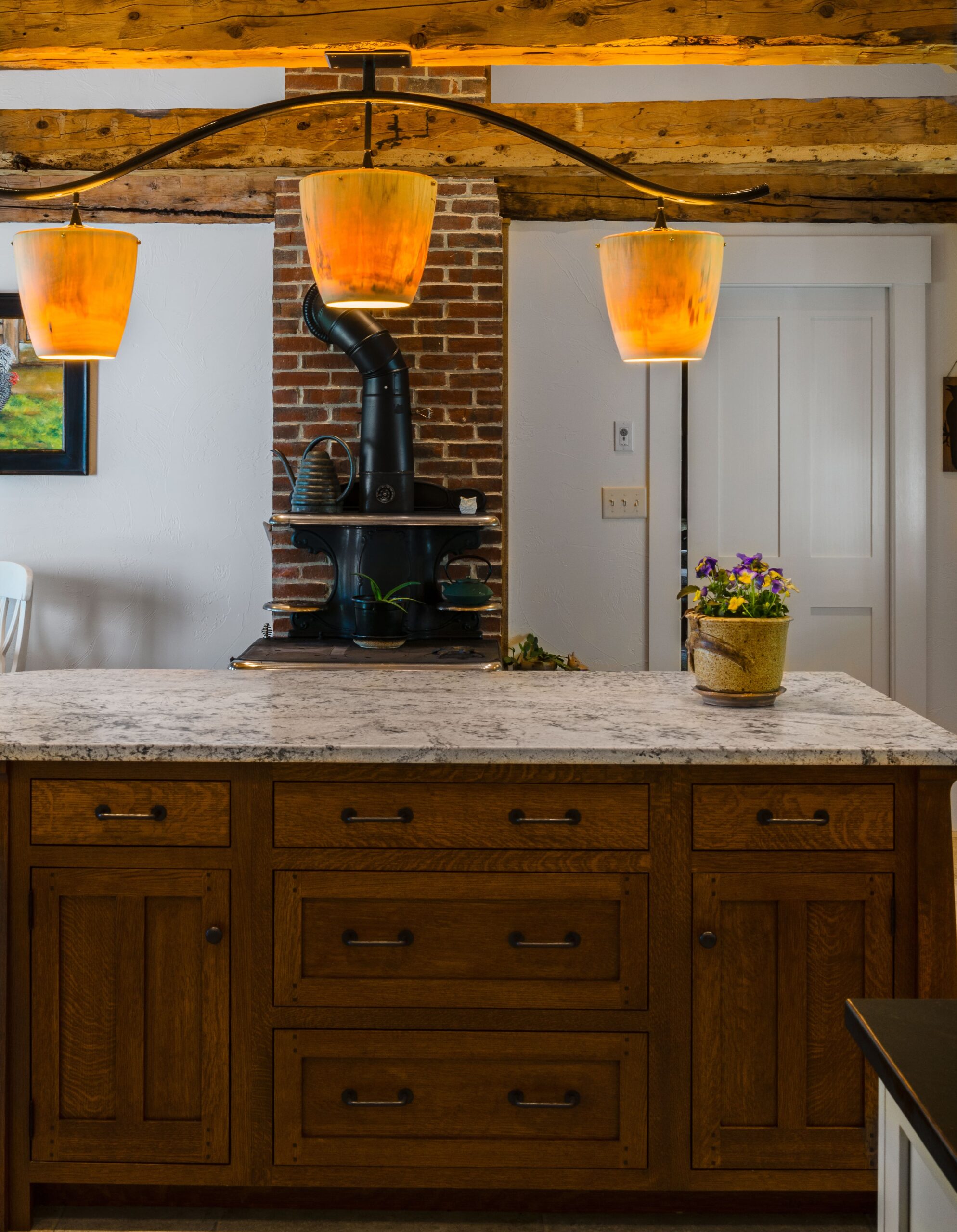 Large light fixture above wooden kitchen island with granite countertops