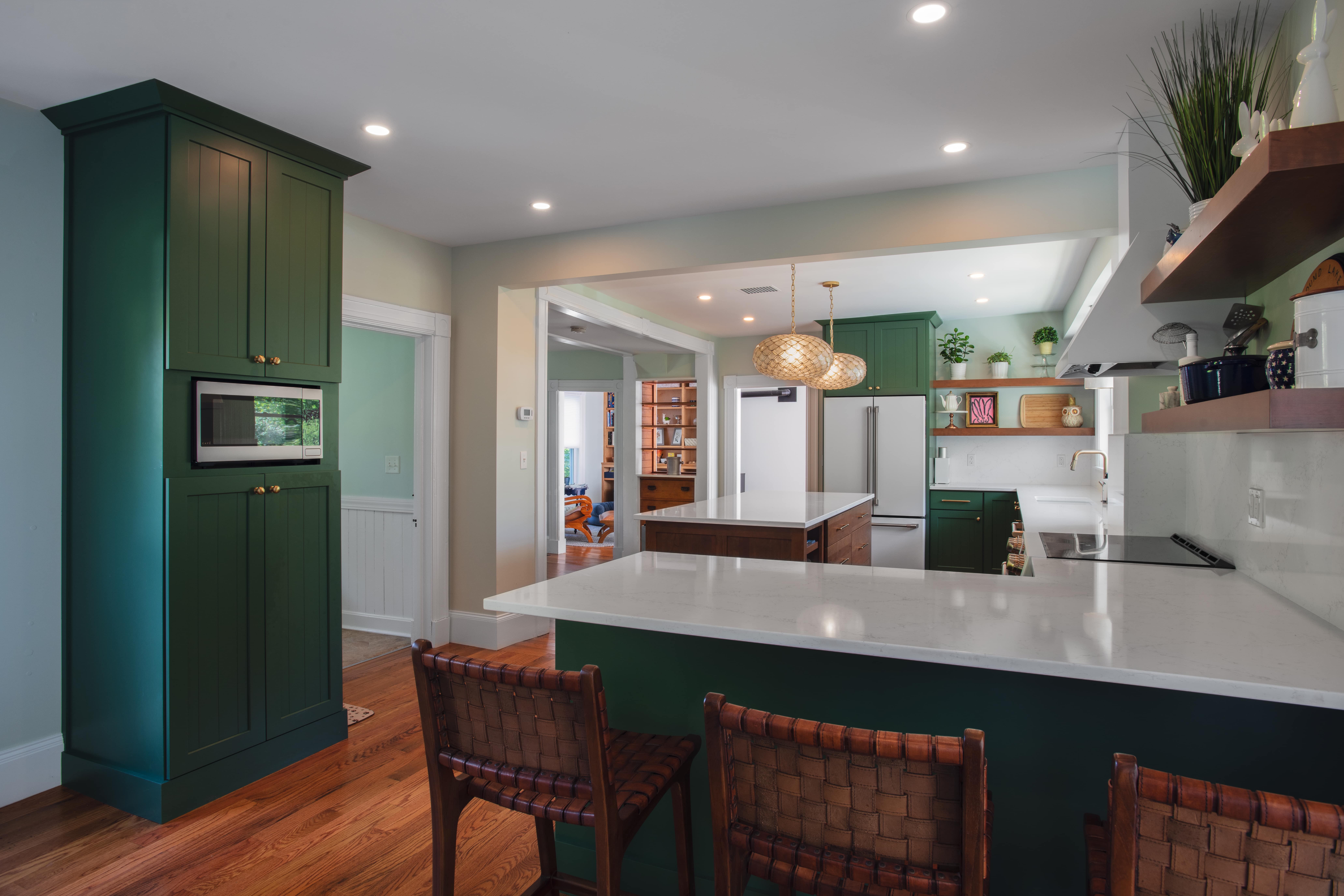Remodeled kitchen with green cabinets and sleek granite countertops