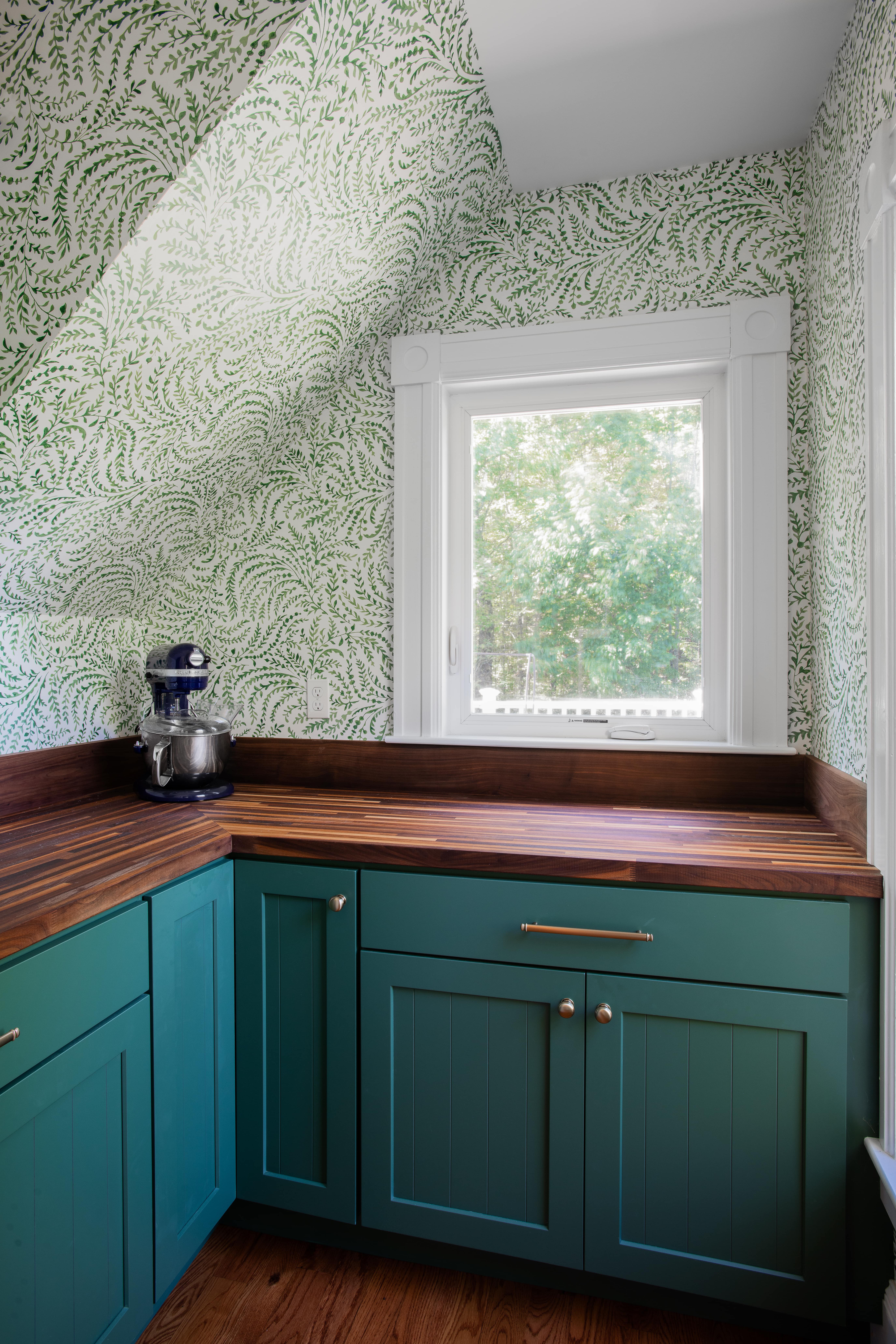 a kitchen with green cabinets, butcherblock counter and a window