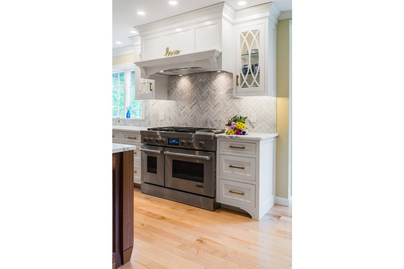 White kitchen renovation with gold brass fixtures and large stove