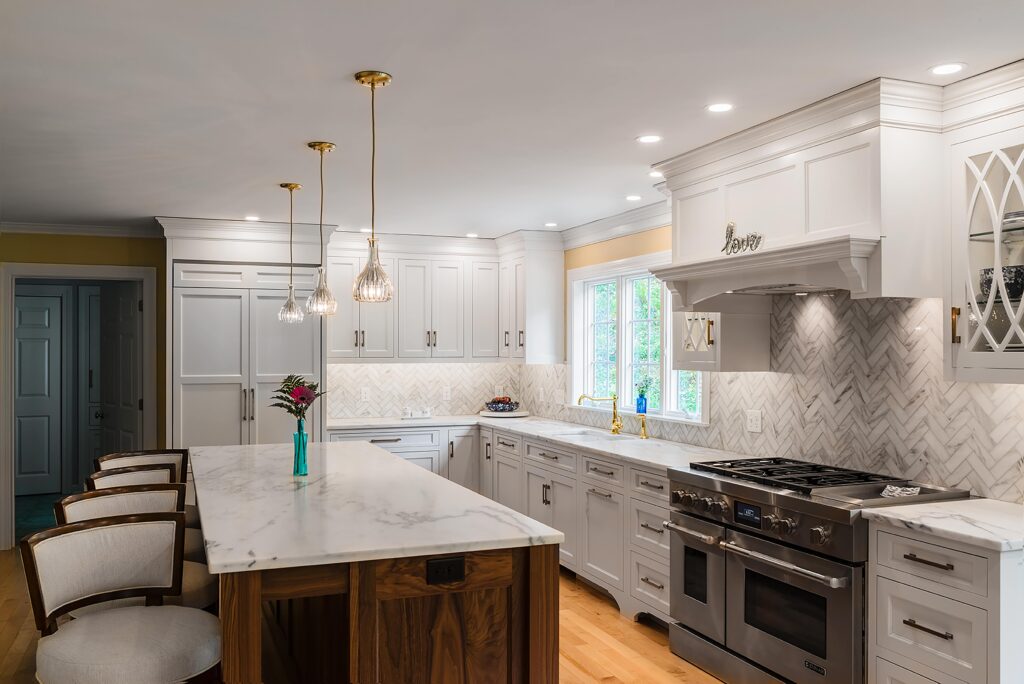 Remodeled kitchen with white cabinets, marble countertops, and a marble-topped woodgrain kitchen island with seating.