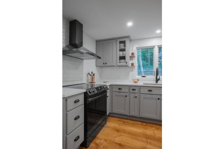 a kitchen with gray cabinets and white counter tops with white subway tile backsplash