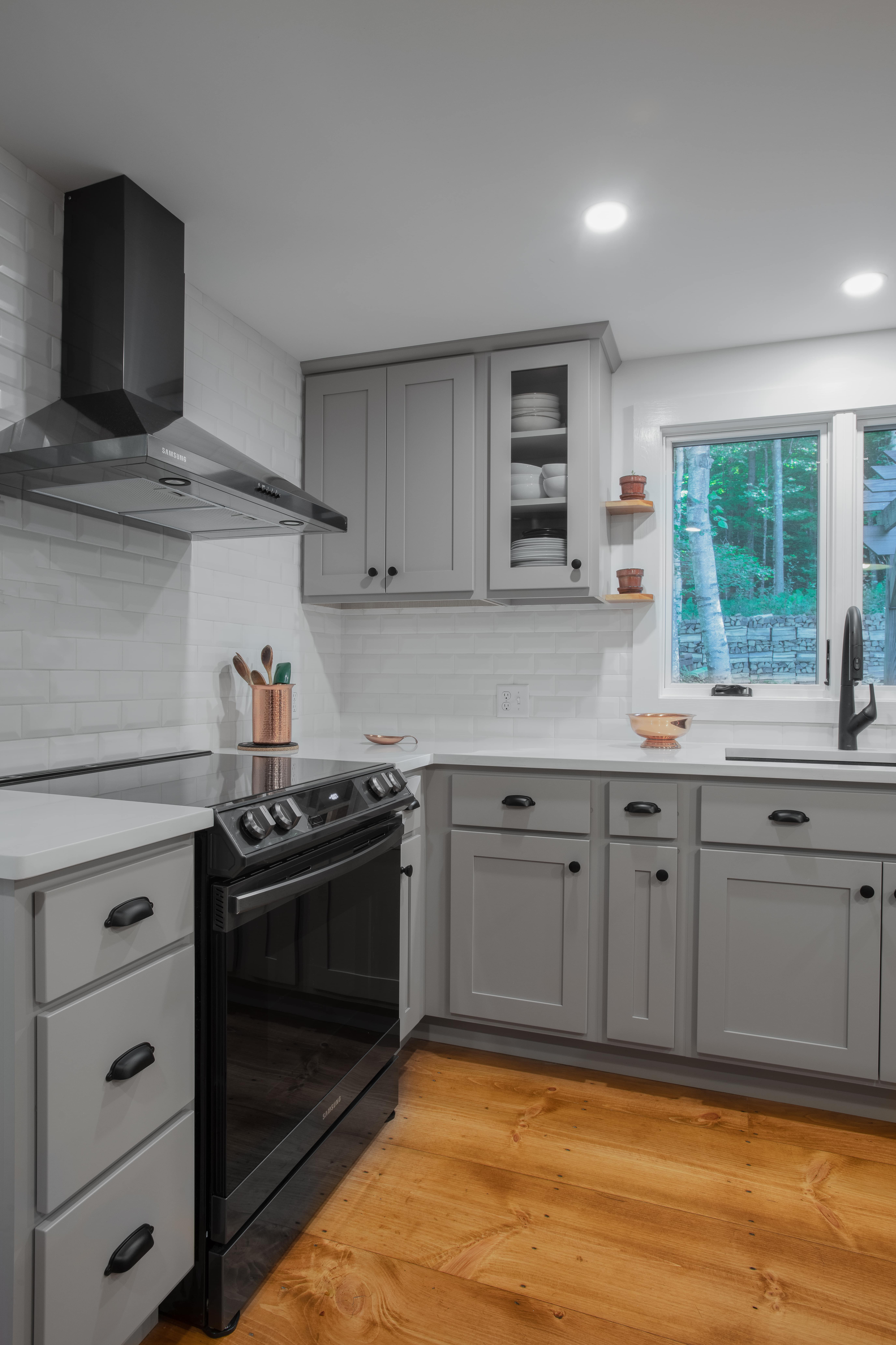 a kitchen with gray cabinets and white counter tops with white subway tile backsplash