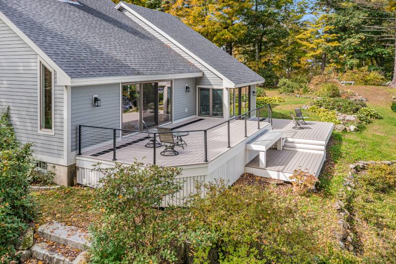 a house with a new attached deck and chairs on it