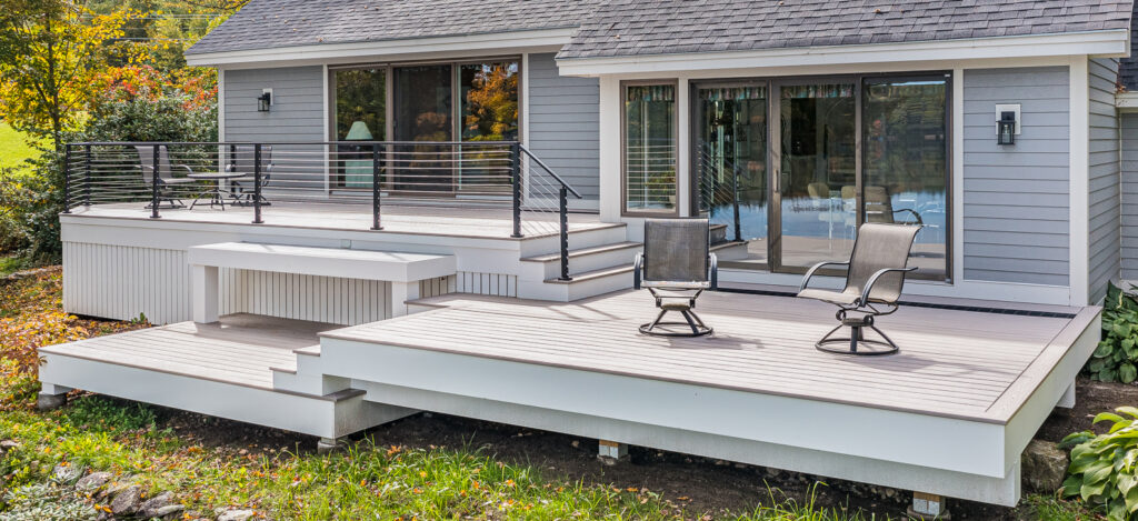 A house with a new attached three-level deck with patio chairs on it