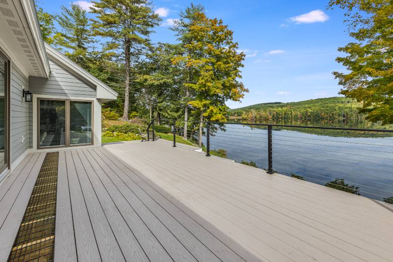 Large deck with metal railing and view of lake