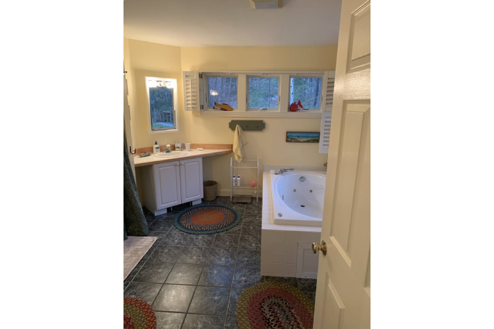 Large outdated ensuite bathroom with black tile floor