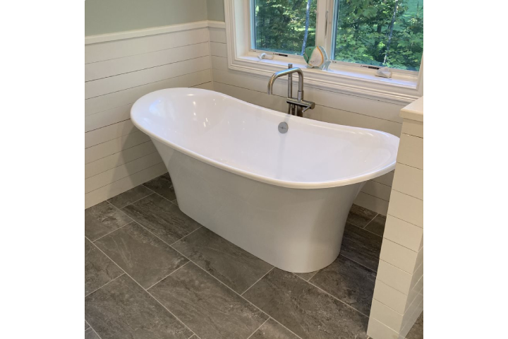 bathroom with large white bath tub next to a window