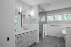 Bathroom remodel with gray wood-look flooring, dual vanity, glass-enclosed shower.