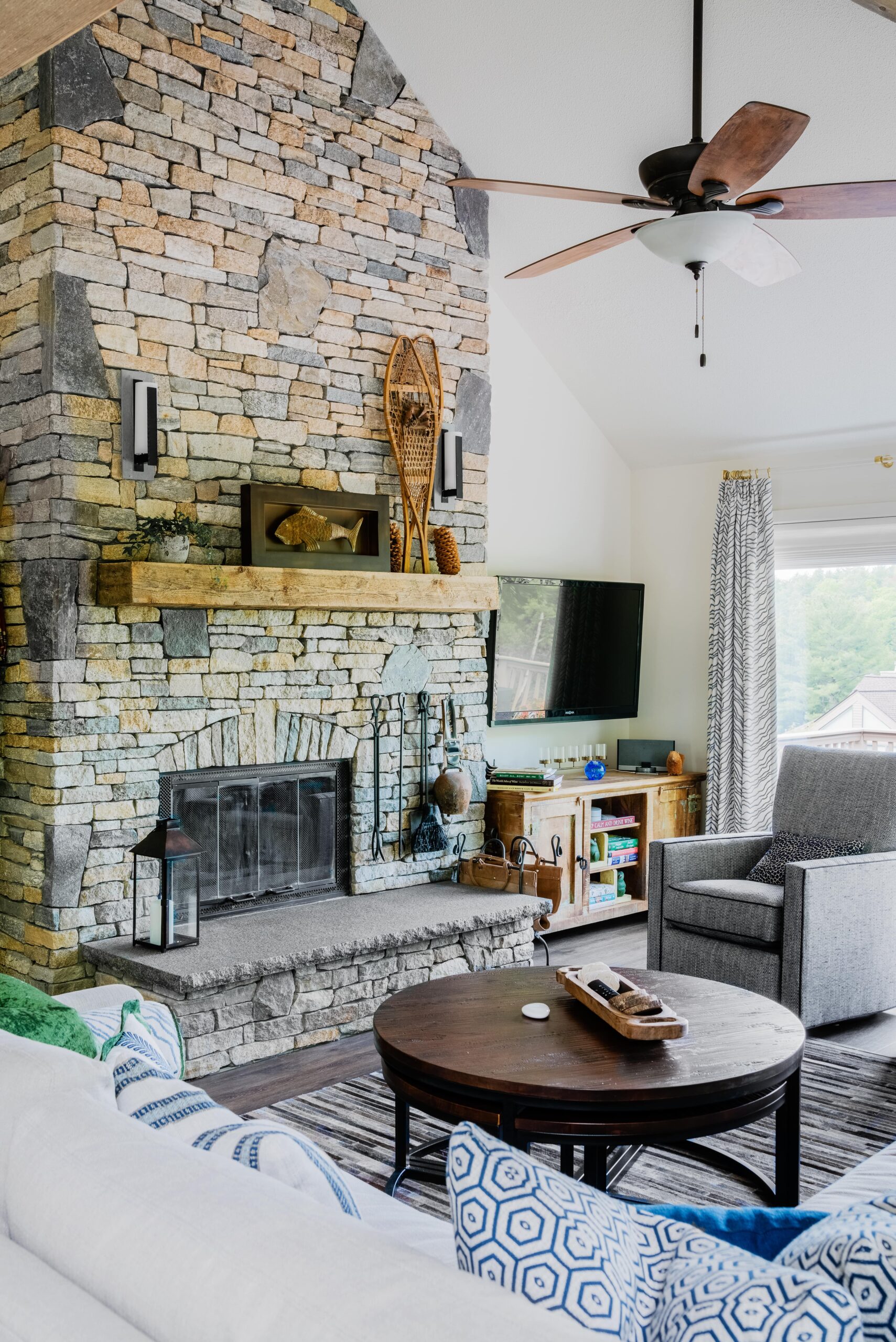 A remodeled living room filled with furniture and a large stone fire place