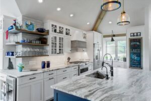 Large renovated kitchen with stone countertops, island with sink, and recessed lighting.