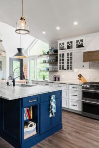 Remodeled kitchen with blue cabinets on island, stone countertops, wood floors, and recessed lighting.