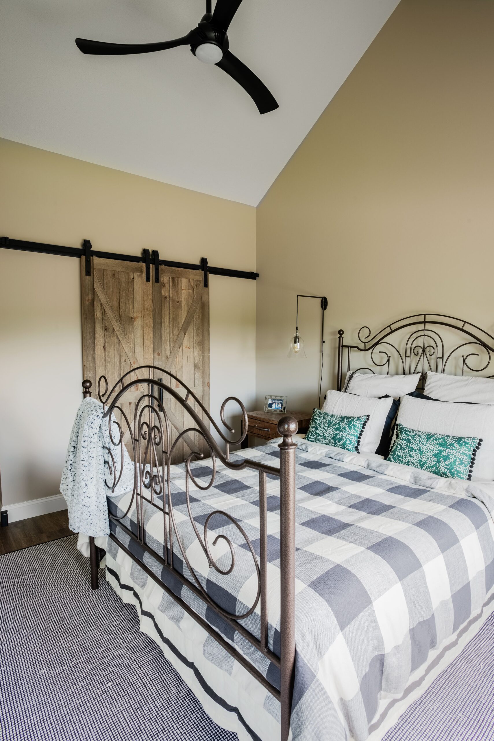 a bedroom with a bed, barn doors, and a ceiling fan