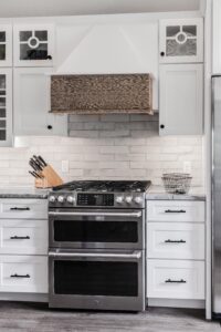 a stove top oven in a white kitchen with marble counters