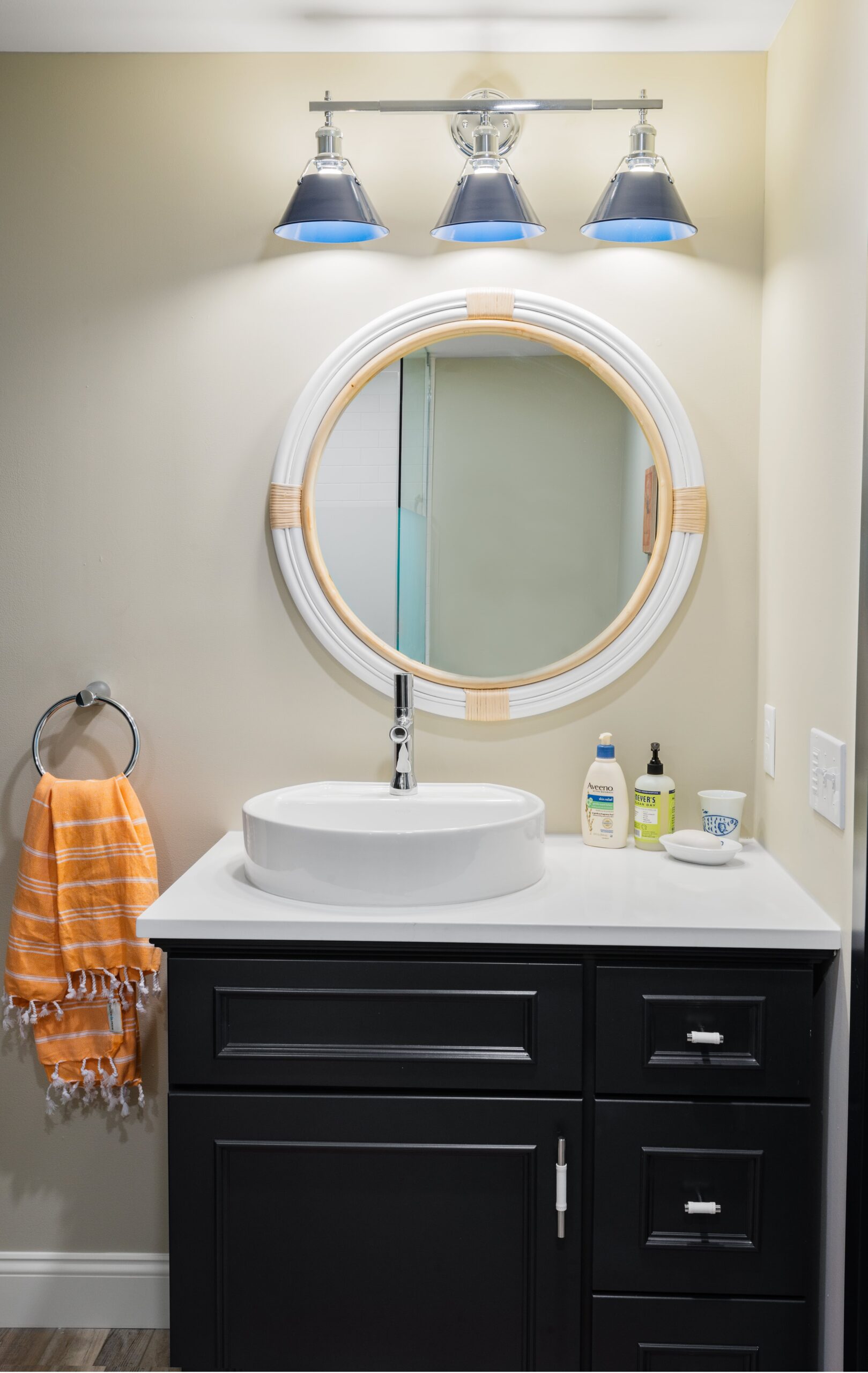 Black bathroom vanity with nautical mirror and modern sink