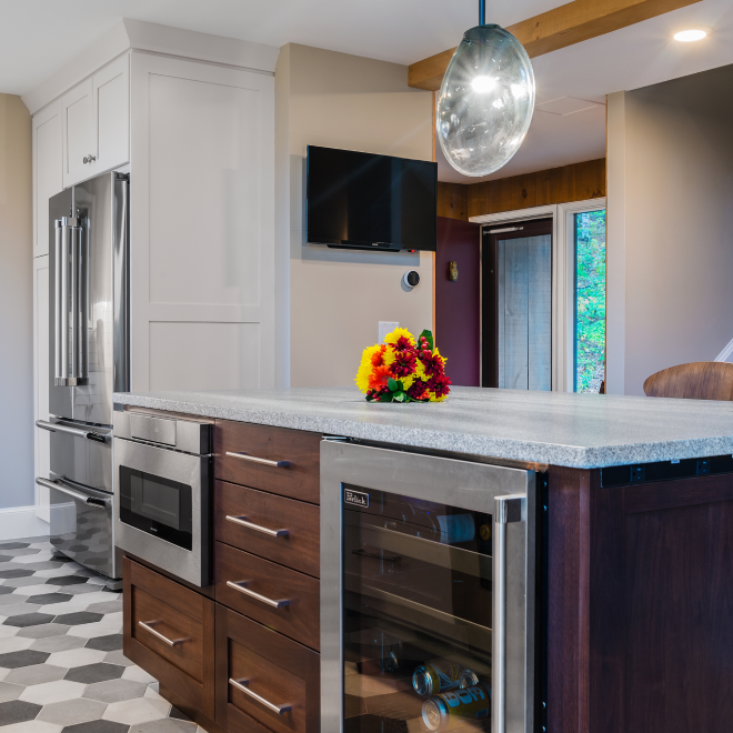 Remodeled kitchen with island, stainless steel appliances, and light granite countertop.