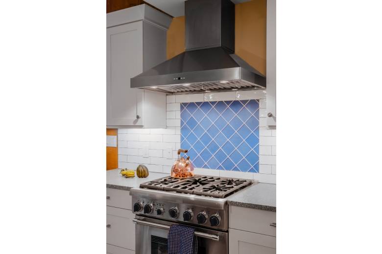 a stove top oven with range and blue tile backsplash