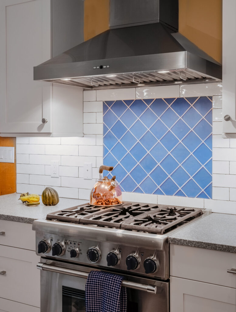 A stove top  and oven with range and custom blue tile backsplash