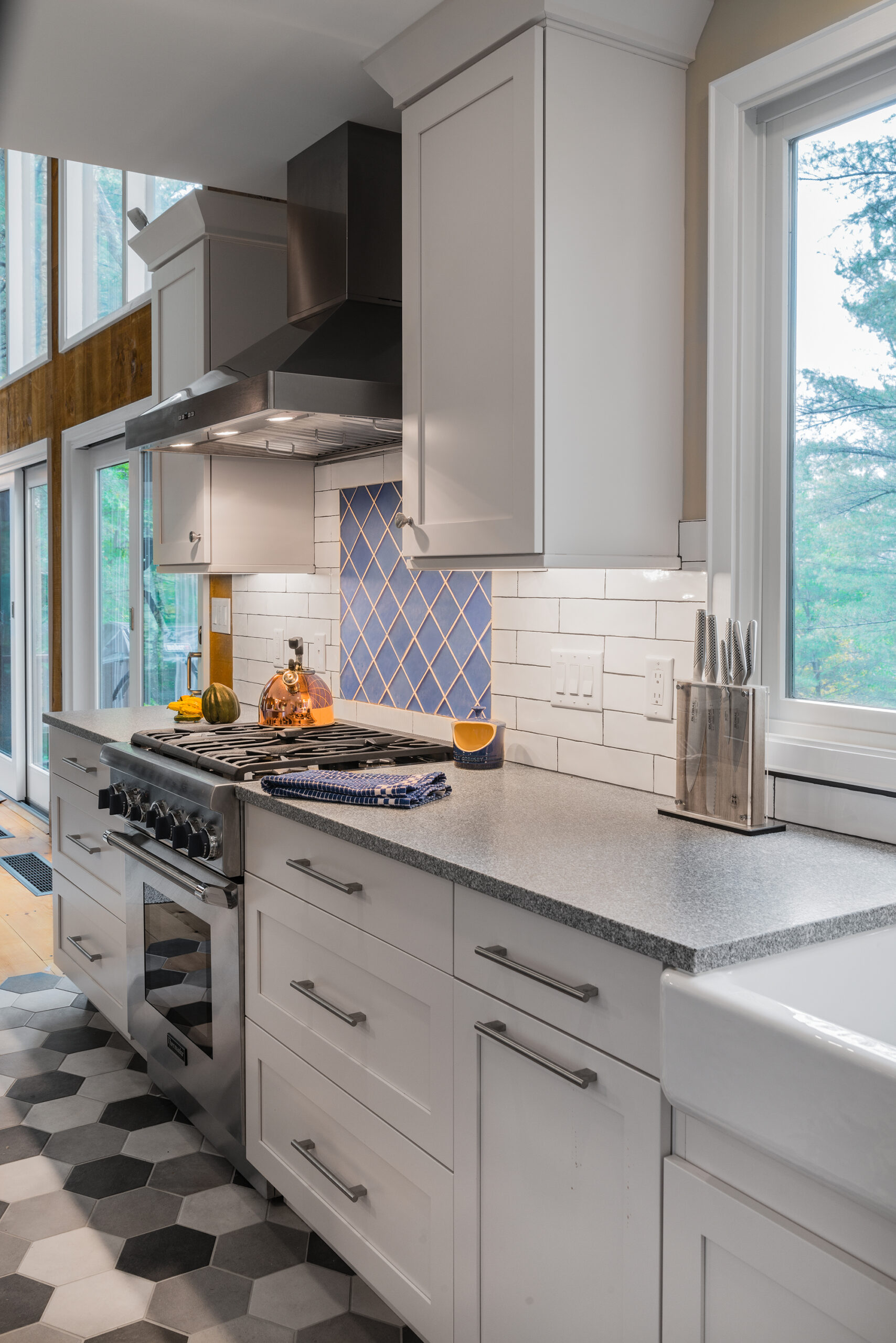 a kitchen with a stove top oven with blue backsplash next to a window