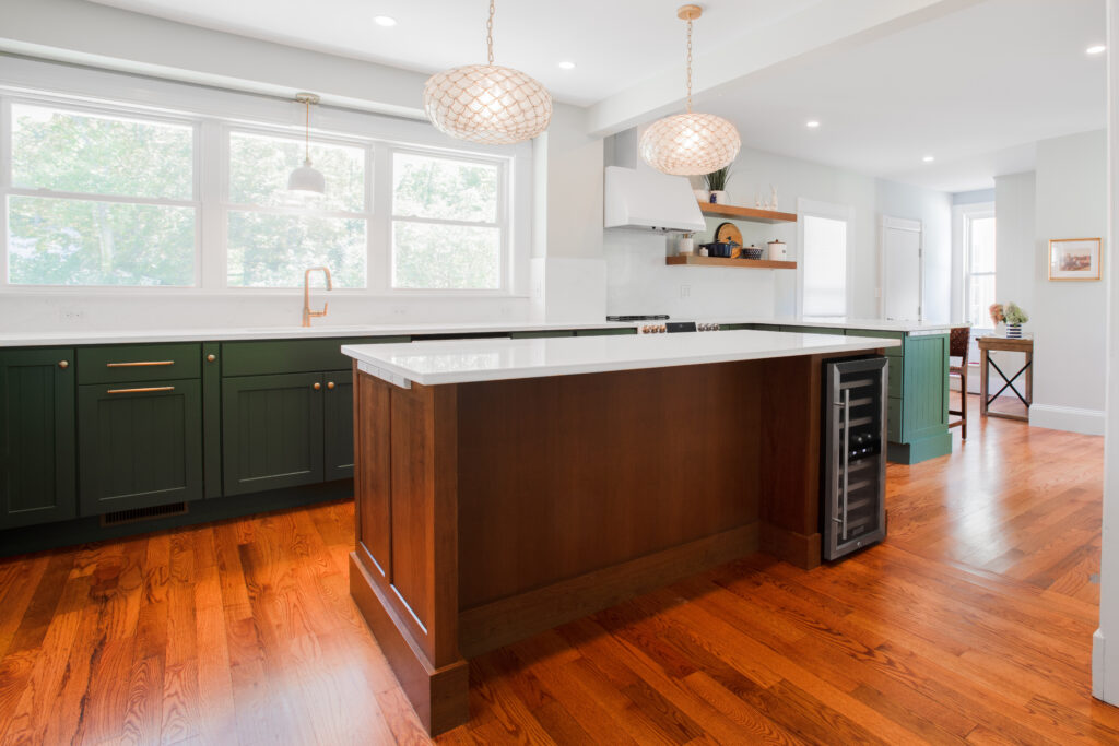 Spacious kitchen island with a deep walnut wood and white counter. Behind it, you can see olive green cabinets along the wall.